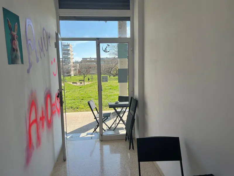 Zona relax de AmOr con mesa y sillas junto a la puerta de entrada, con vistas al parque